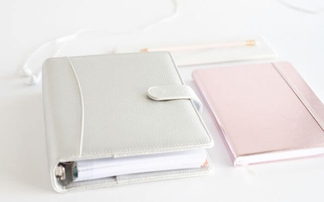 A grey notebook and a pink notebook on a table